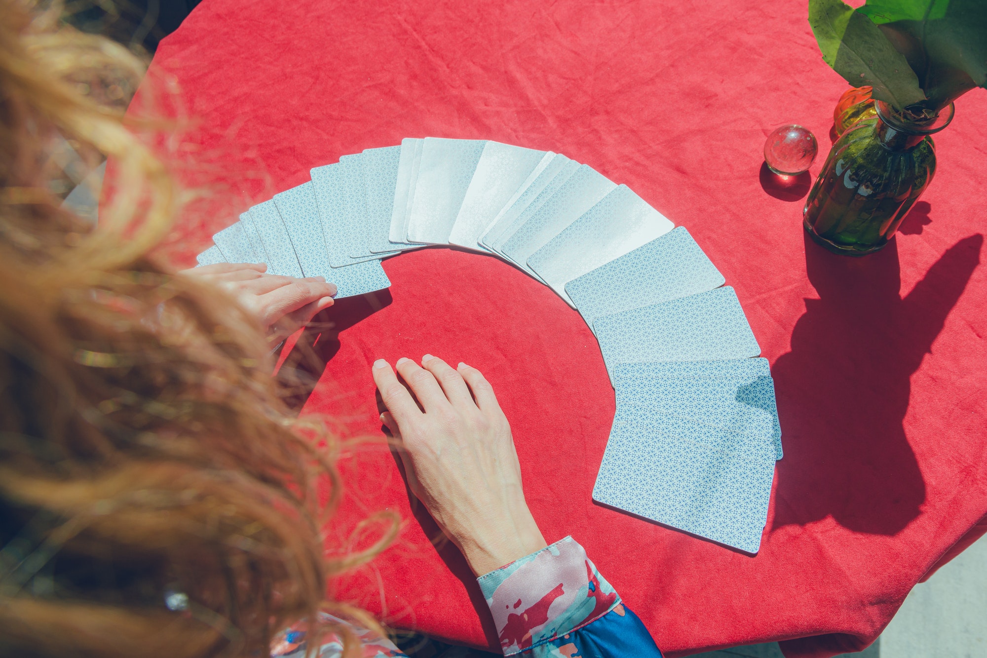 top and rear view of unrecognizable female hands taking tarot card from deck on table
