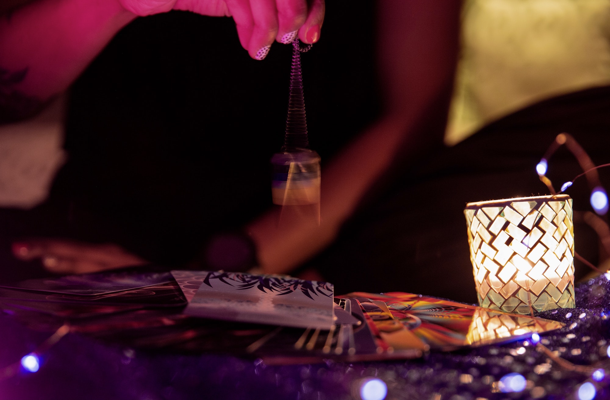 A woman swinging a pendulum over a tarot card for a reading