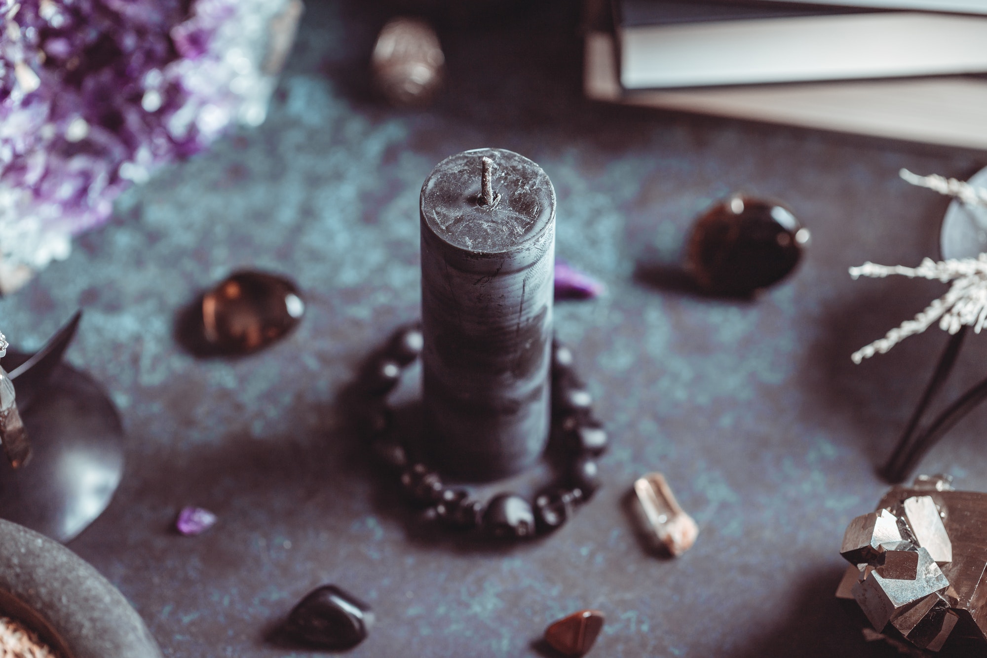 Black candle on a witch's altar for a magical ceremony among crystals and black candles.