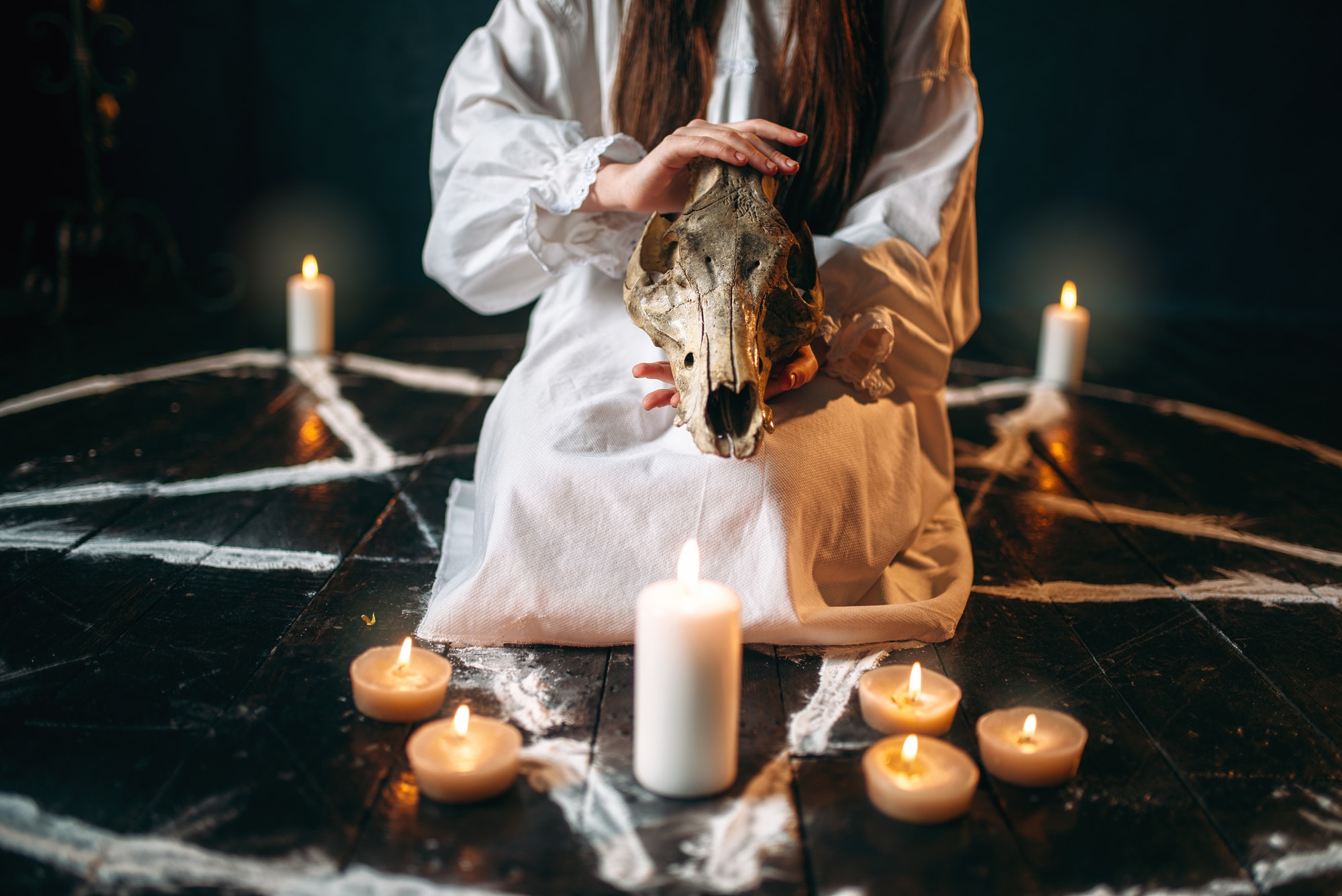 Female person holds skull in hands, magic ritual
