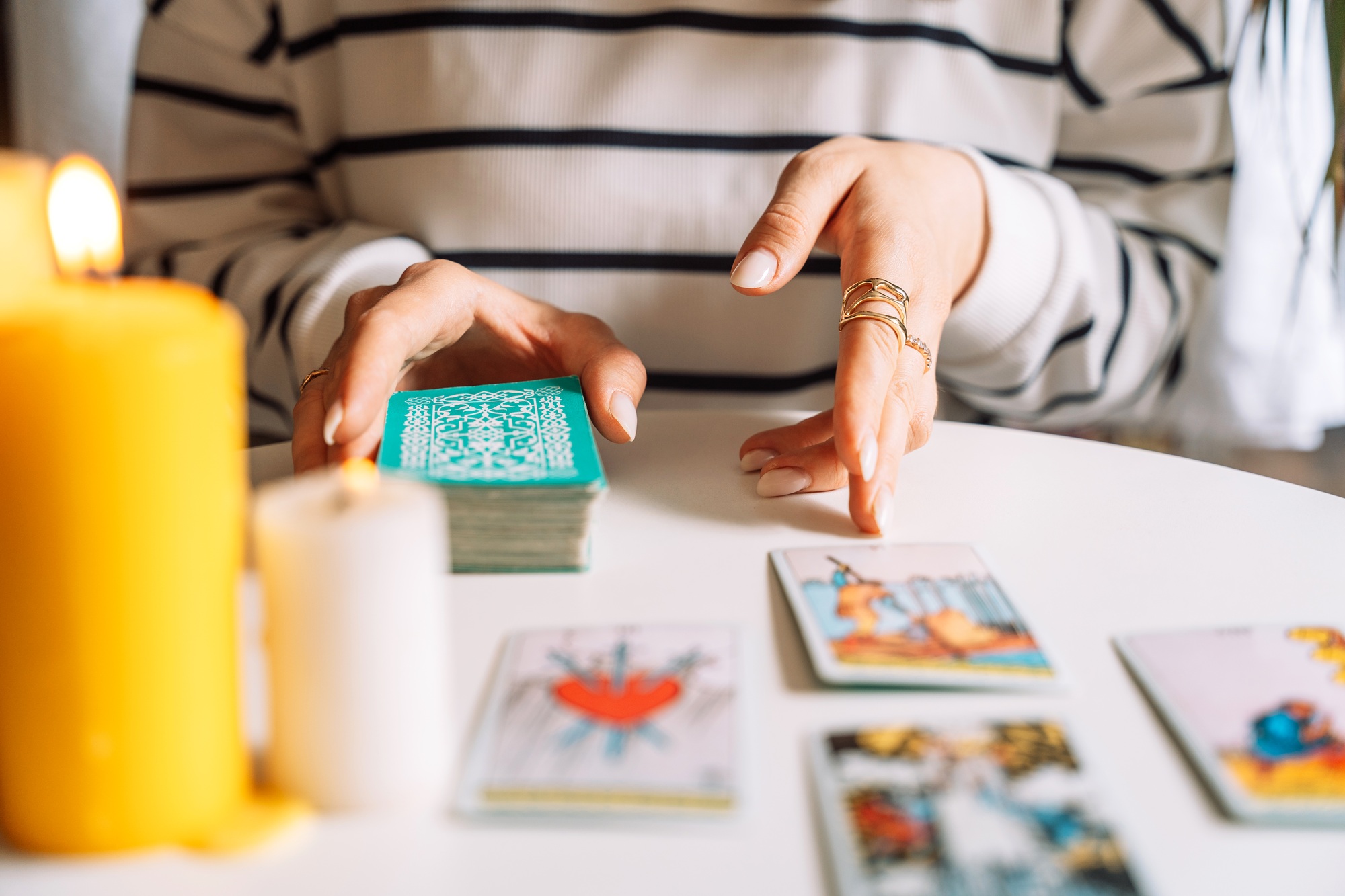Lady tarot reader tells fortunes with tarot cards on a white table with burning candles